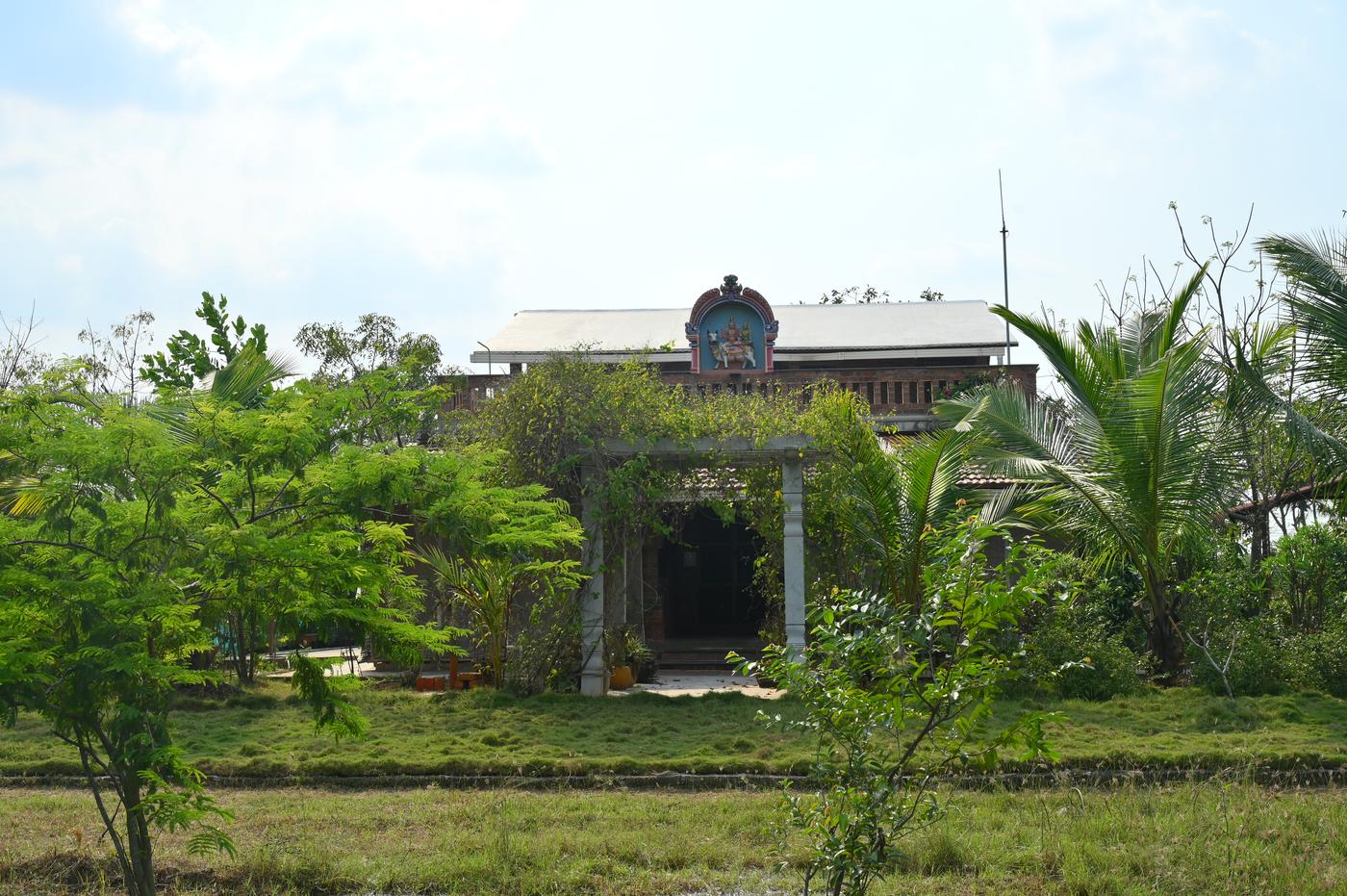 Mutram Heritage Stay seen across the paddy fields — front elevation of the heritage farm stay near Kanchipuram